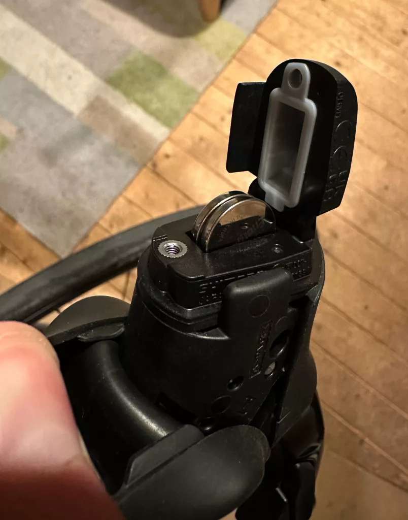 Di2 shifter with battery hood open showing two batteries being replaced