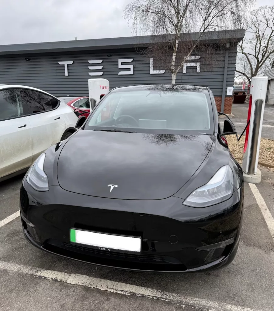 A Tesla Model Y plugged in at a UK Tesla Supercharger station
